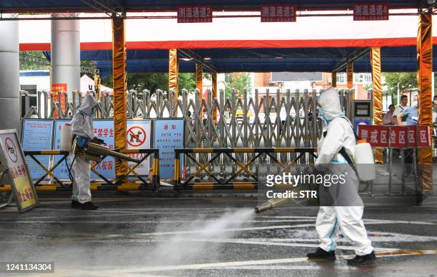 This photo taken on June 5, 2022 shows workers spraying disinfectant at a school before the annual "Gaokao" or college entrance examinations in...