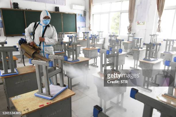 This photo taken on June 5, 2022 shows a worker spraying disinfectant at a school before the annual "Gaokao" or college entrance examinations in...
