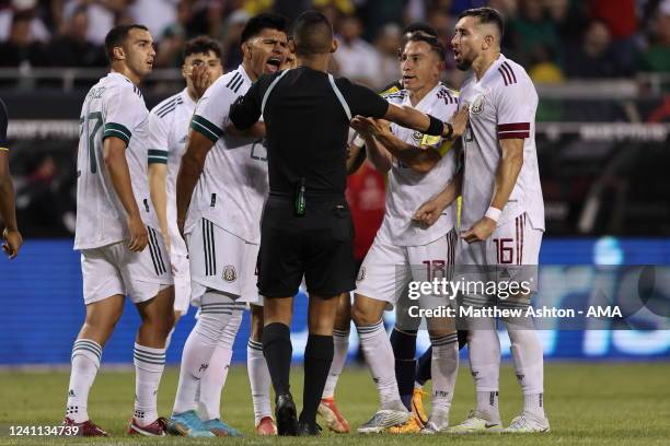 Referee Oliver Vergara from Panama controls Mexico players arguing with him over a penalty decision during an International Friendly game between...