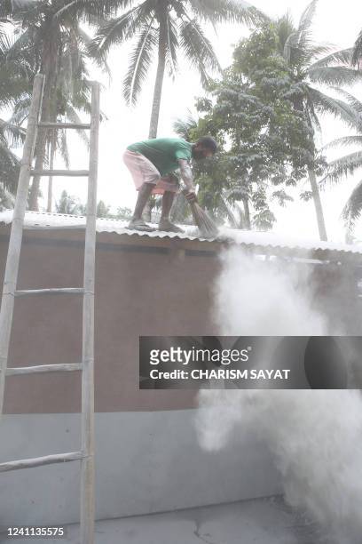 Resident sweeps away ash from the roof of their house in Juban town, Sorsogon province on June 6 a day after the eruption of Bulusan volcano. - The...