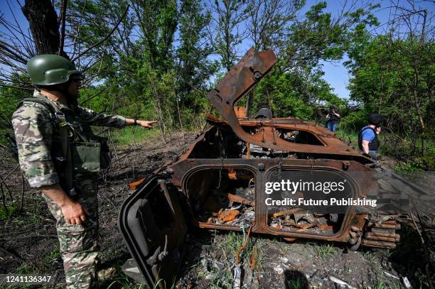 Ukrainian serviceman points at a destroyed Russian BMP-2 infantry fighting vehicle by the roadside between Zelene Pole and Novopil villages, Donetsk...