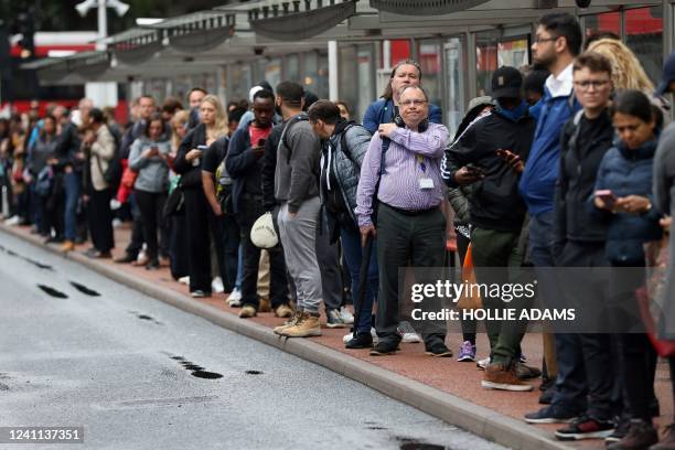 Commuters wait at a bus stop outside Victoria train station in London on June 6 during a 24-hour strike by nearly 4,000 London Underground station...