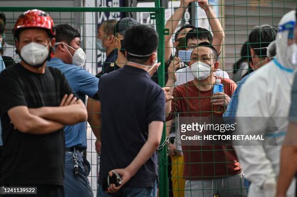 Angry residents confront officials from behind a fence erected in a neighbourhood compound in the Xuhui district of Shanghai on June 6, 2022. -...