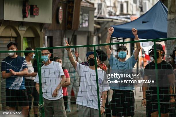 Angry residents gesture from behind a fence erected in a neighbourhood compound in the Xuhui district of Shanghai on June 6, 2022. - Residents stuck...