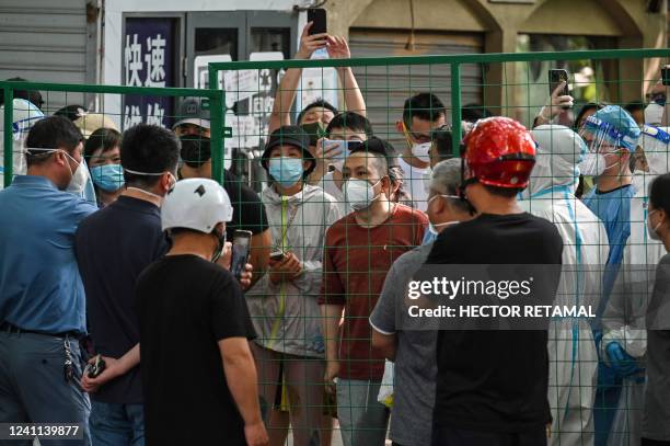 Angry residents confront officials from behind a fence erected in a neighbourhood compound in the Xuhui district of Shanghai on June 6, 2022. -...