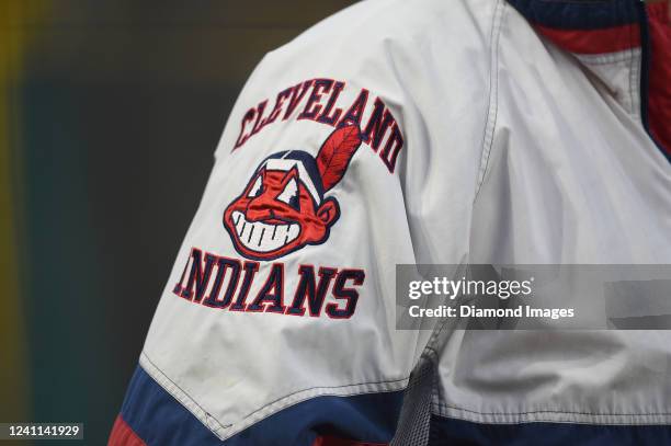 Cleveland Guardians fan wears a jacket displaying the prior name and Chief Wahoo logo during the eighth inning against the Cincinnati Reds at...