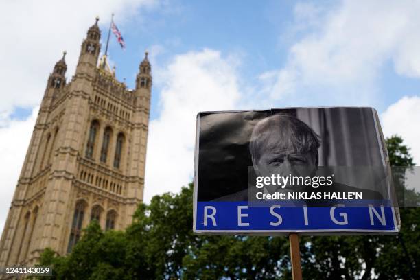 Photograph taken on June 6, 2022 shows a board reading "Resign" and picturing Britain's Prime Minister Boris Johnson in front of The House of...