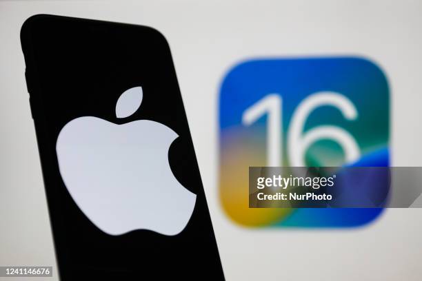 Apple logo displayed on a phone screen and iOS 16 logo displayed on a screen in the background are seen in this illustration photo taken in Krakow,...