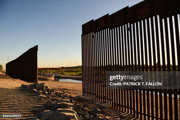 The sun sets behind a gap along the border wall at the Morelos Dam between the US and Mexico in Yuma, Arizona on May 31, 2022. - The stream of...