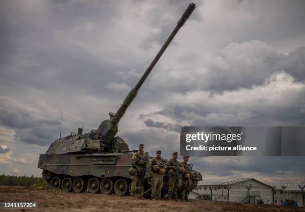 June 2022, Lithuania, Pabrade: Soldiers stand in front of an armored self-propelled artillery piece of the Bundeswehr howitzer 2000 type used by the...