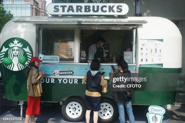 Tourists buy drinks in front of a Starbucks mobile coffee cart parked beside West Lake in Hangzhou, East China's Zhejiang Province, June 7, 2022. It...