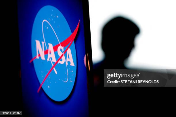 The silhouette of US engineer and NASA astronaut Megan McArthur is seen past the NASA logo in the Webb Auditorium at NASA headquarters in Washington,...