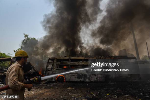 Firefighters try to douse a fire at the bus parking bay in Timarpur, on June 7, 2022 in New Delhi, India.