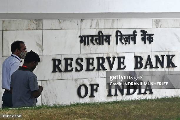 Pedestrians walk past the Reserve Bank of India signage at its headquarters in Mumbai on June 8, 2022. - India's central bank on June 8 hiked rates...
