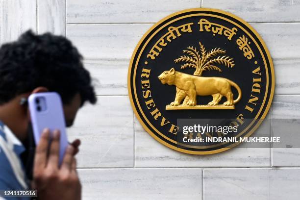 Man speaks on a mobile phone while walking past the Reserve Bank of India signage at its headquarters in Mumbai on June 8, 2022. - India's central...