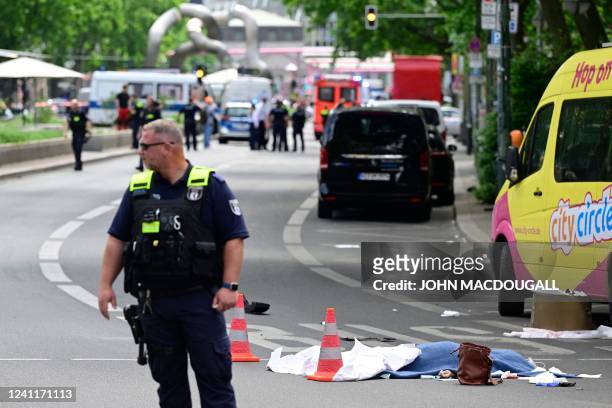 Police officer stands near the body of a dead person at a cordoned-off area where a car ploughed into a crowd near Tauentzienstrasse in central...
