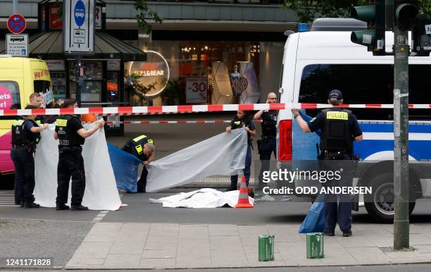 Police shields the body of a victim at the site where one person was killed and eight injured when a car drove into a group of people in central...