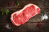 raw strip loin steak on white wooden background in rustic style