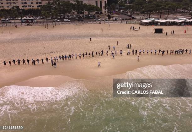 Aerial view of participants joining hands to form a long human chain along Leme beach, during an event to promote cleaner beaches and marine...