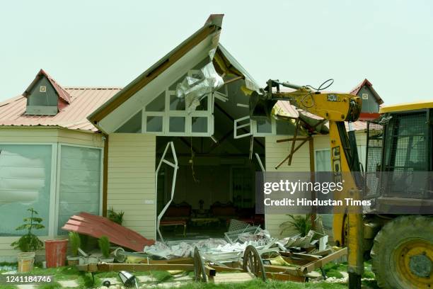 Bulldozer demolishes unauthorised farmhouse during a demolition drive by the Noida Authority against the illegal farmhouses in Sector-132 along...