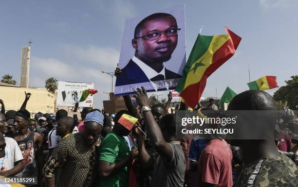 Protestors hold flags of the Senegal and a portrait of the opponent and Mayor of Ziguinchor Ousmane Sonko as they attend a rally of the Senegalese...