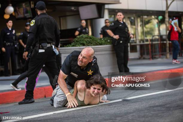 Secret Service police officer wrestles a protester to the ground after she ran towards a motorcade on its way to the LA Convention Center where North...