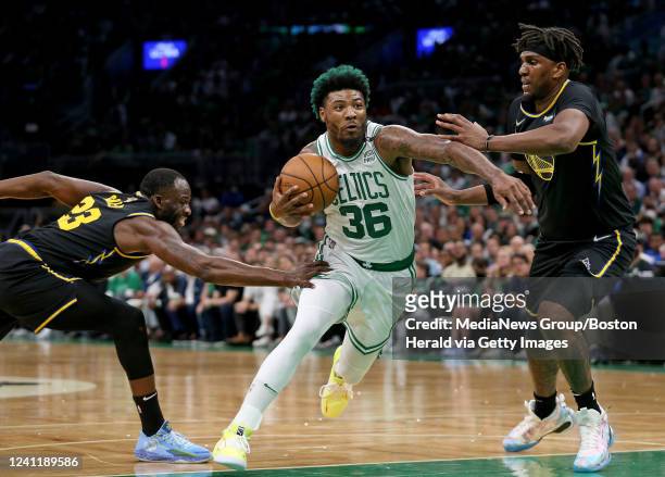Marcus Smart of the Boston Celtics takes the ball in-between James Wiseman and Kevon Looney of the Golden State Warriors during the first half of...