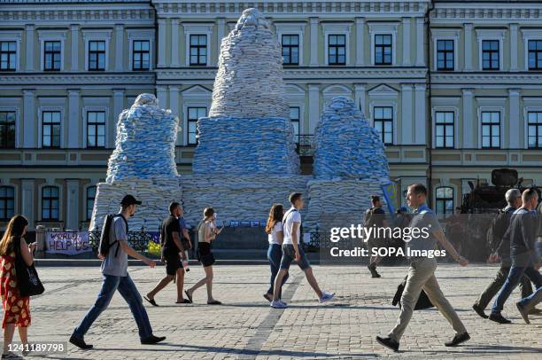 People walk past the monument to Princess Olga, the Holy Apostle Andrew the First-Called, and the Enlighteners Cyril and Methodius covered by...