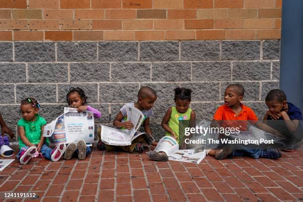 Group of cousins, some being siblings, read the Express newspaper while waiting for the public bus in Anacostia with their grandmother, Melissa...