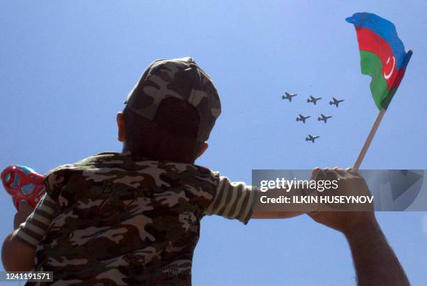 An Azeri boy waves the national flag during a military parade in Baku on June 26, 2011. Azerbaijan paraded thousands of soldiers and hundreds of...