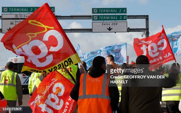 Paris Charles de Gaulle airport employees wave trade union flags as they stage a strike to demand higher wages at Roissy Charles De Gaulle Airport,...