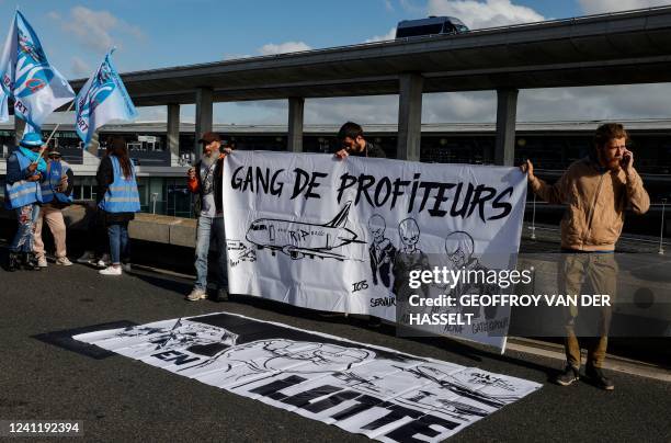 Paris Charles de Gaulle airport employees hold a banner which reads "Gang of Profiteers" outside a terminal as they stage a strike to demand higher...