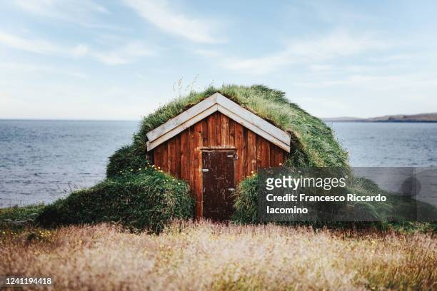 lonely isolated small house with grass rooftop and ocean on background - hut stock pictures, royalty-free photos & images
