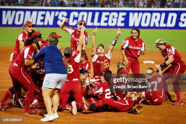 Jocelyn Alo of the Oklahoma Sooners is handed the NCAA trophy as Alyssa Brito and the rest of the team celebrate their win over the Texas Longhorns...