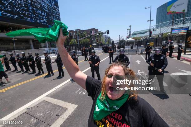 An Abortion Rights protester waves a green scarf in front of police officers as they clear the street during a protest outside the Convention Center...