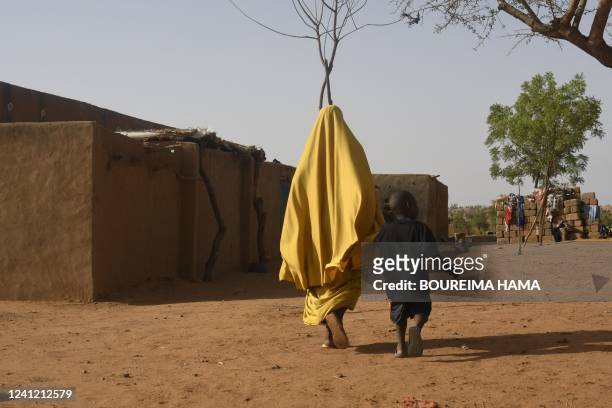 Woman and her child walk through the village of Garbey Kourou, southwestern Niger, on June 9, 2022. - Nigerien President Mohamed Bazoum traveled on...