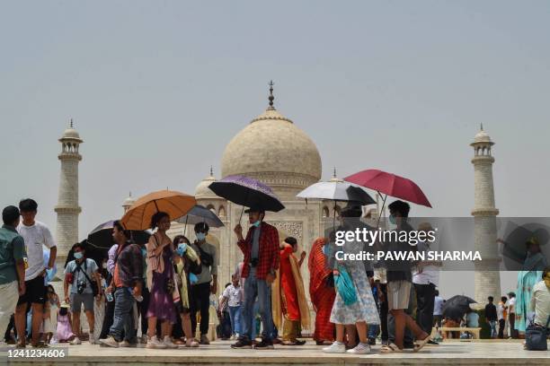 Tourists shelter from the sun under umbrellas while visiting the Taj Mahal during a hot summer day in Agra on JUne 11, 2022.