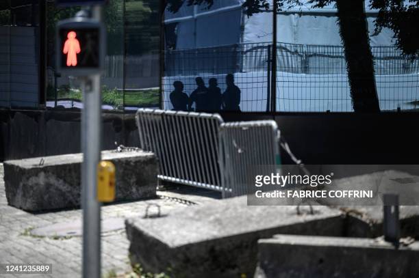 Police officers are seen in silhouette guarding the entrance of the headquarters of the World Trade Organization on the eve of the WTO Ministerial...
