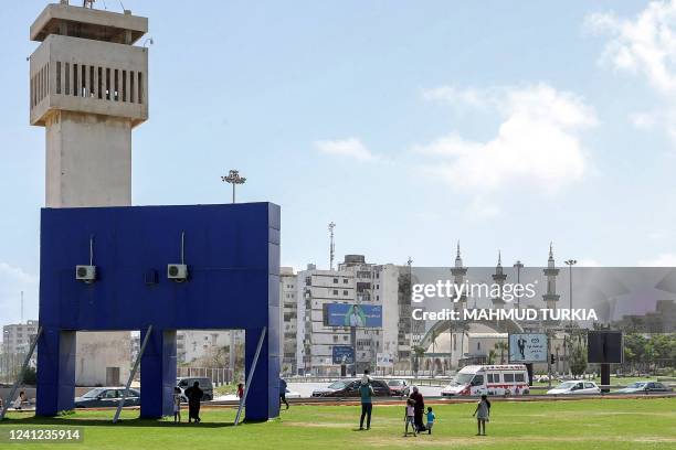 Woman walks with children on a lawn at the Souk al-Thalath district in the centre of Libya's capital Tripoli on June 11 after clashes between two...