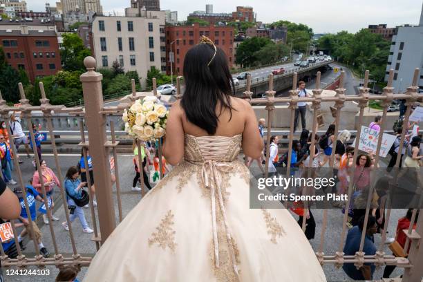 Girl in a formal dress watches as people march across the Brooklyn Bridge to protest against gun violence in the March for Our Lives march and rally...