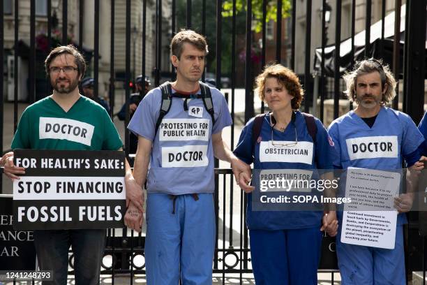 Healthcare professional demonstrators hold placards during the protest. Healthcare professionals have glued themselves outside Downing Street to...