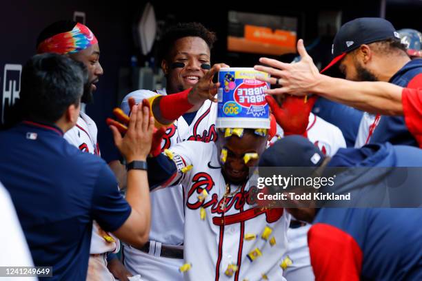 Ronald Acuna Jr. #13 of the Atlanta Braves dumps a bucket of Double Bubble bubble gum on Ozzie Albies after Albies hit a grand slam during the...