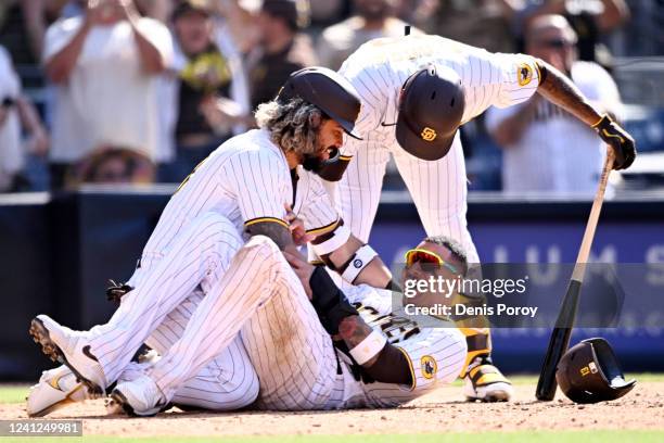 Manny Machado of the San Diego Padres celebrates with Jorge Alfaro and Jose Azocar after Machado scored in the 10th inning of game one of a...