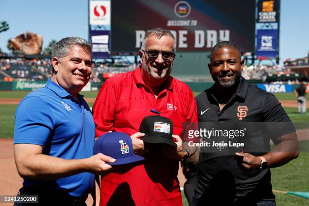 Erik Braverman, Roscoe Mapps and former umpire Dale Scott hold Pride hats prior to the game between the Los Angeles Dodgers and the San Francisco...