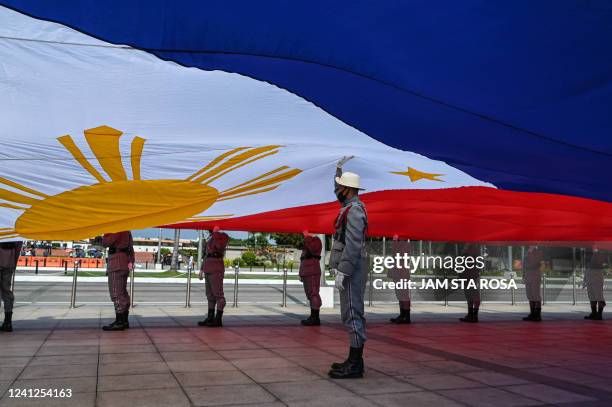 Honour guards carry a giant Philippine flag during a wreath-laying ceremony on the country's 124th Independence Day at Rizal Park, Manila on June 12,...