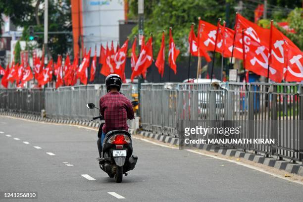 Motorist rides past a row of communist party flags placed along the roadside at Thiruvananthapuram in India's Kerala state on June 12, 2022.