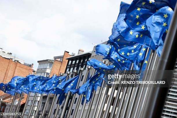 This photograph taken on June 12, 2022 shows European flags in front of Berlaymont Building, headquarters of the European Commission in Brussels.