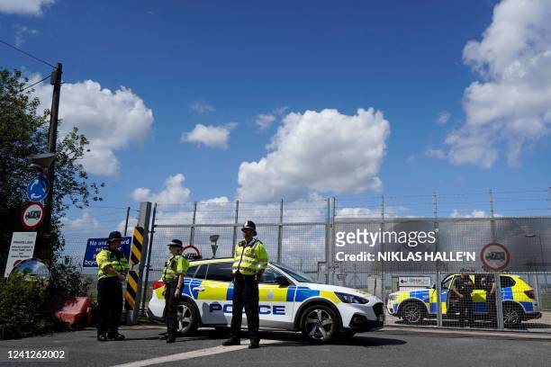 Police officers guard a fence, blocking off the access road to the Brook House immigration removal centre beside Gatwick Airport, south of London on...