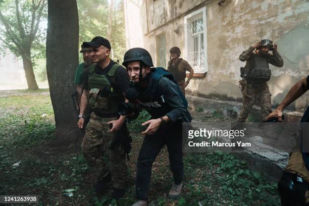 Soldiers and journalists flee for cover after a bombardment hit nearby, sending dust in the air, in Lysychansk, Ukraine, Saturday June 11, 2022.