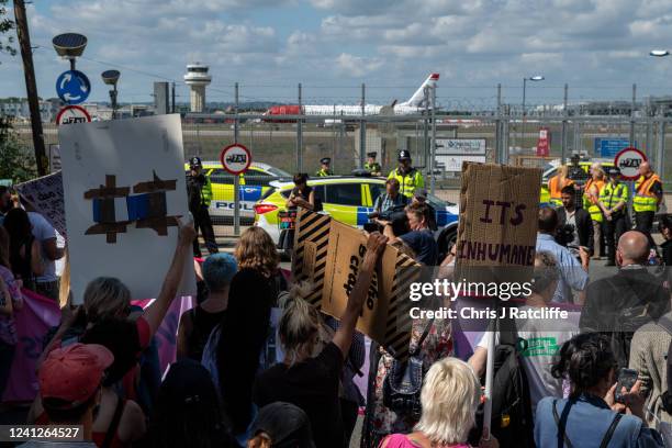 Protesters chant and hold placards against the UK deportation flights to Rwanda near Brook House Immigration Removal Centre on June 12, 2022 in...